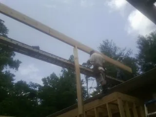 Carpenter setting a ridge beam over a new addition frame — Ice Dam Removal by Roofing Brothers in Littlerock